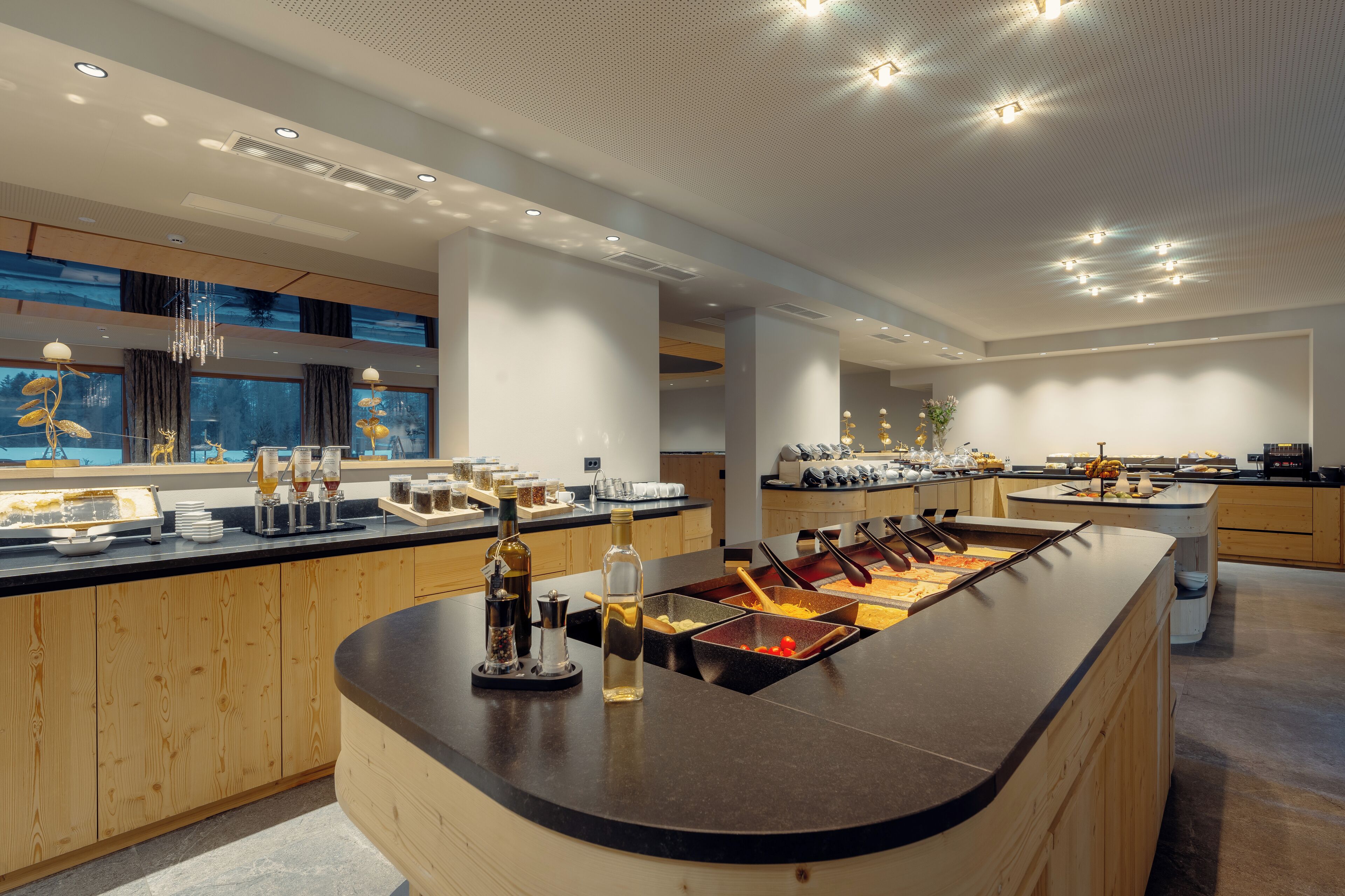 Une cuisine moderne dotée d’un îlot central, de meubles en bois et d’une grande fenêtre donnant sur un paysage magnifique.