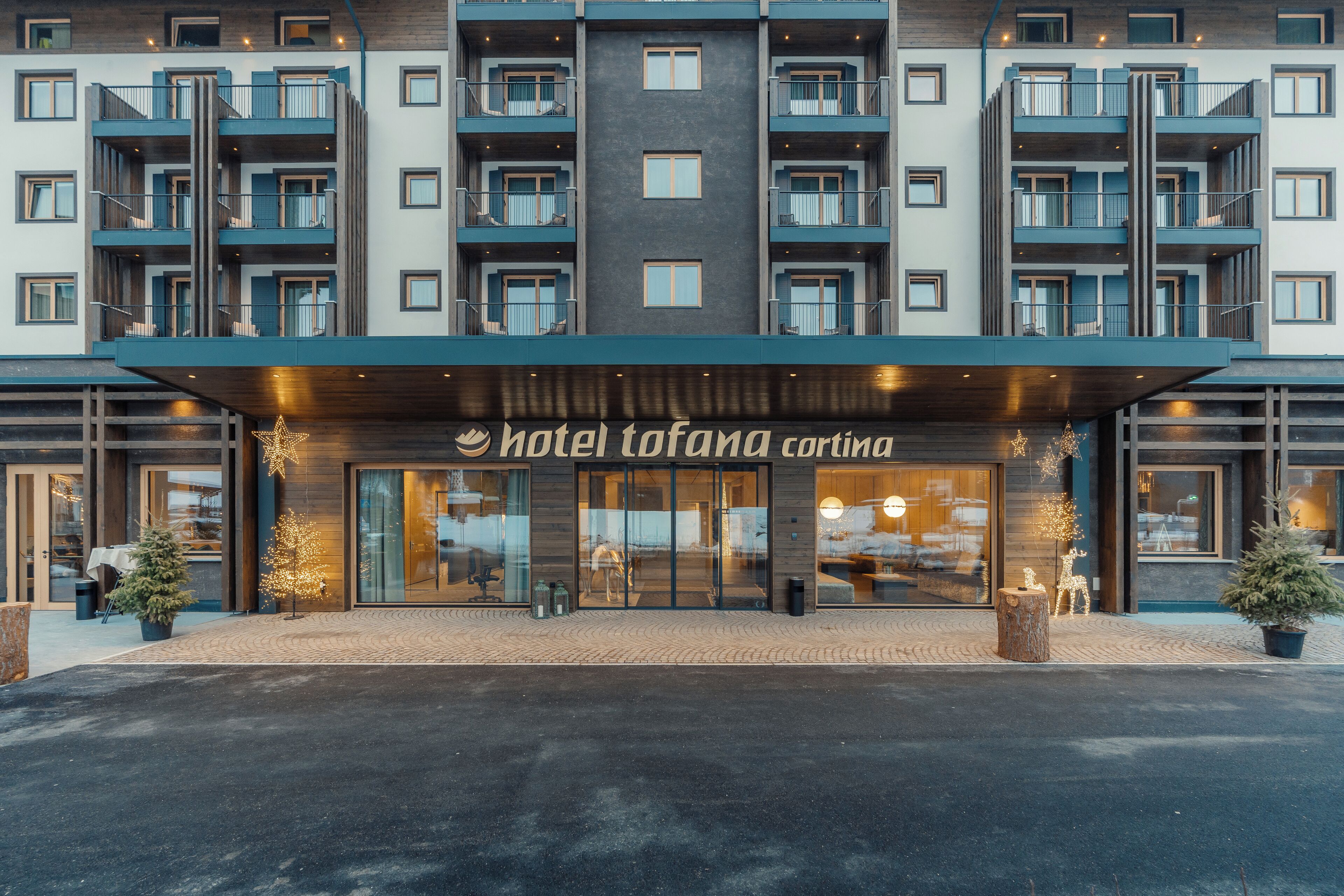A multi-story hotel with balconies, a central entrance, and a sign reading "Hotel Tofana Carintia".