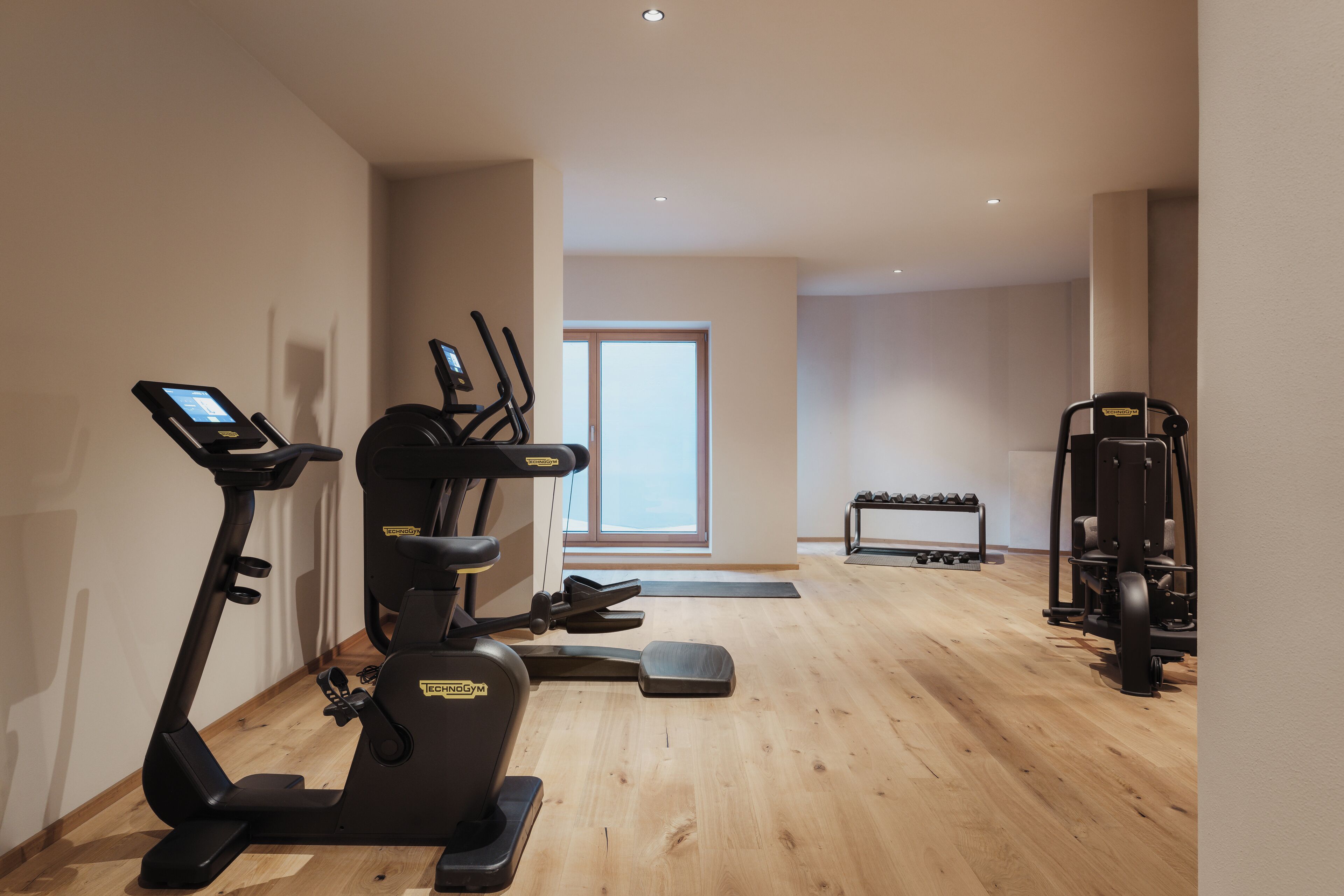 A gym with cardio machines, weightlifting equipment, and a bench.