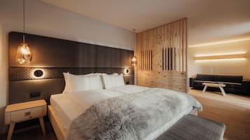 Ein modernes Schlafzimmer mit einem großen Bett, einem Holzkopfende, einem Nachttisch, einer Kommode und einer Sitzecke mit Sofa und Couchtisch.