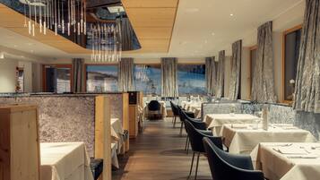 A restaurant with wooden ceiling, marble walls, and tables set for dining.