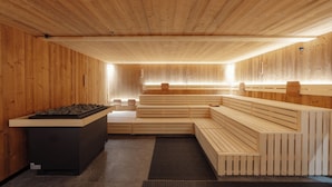 Una sauna con bancos de madera y un elemento calefactor central.