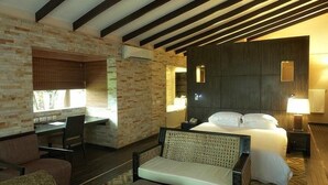 A hotel room with a bed, a desk, and a chair. There is a window with blinds, a lamp, and a mirror on the wall. - Epe Resort and SPA (Epe)