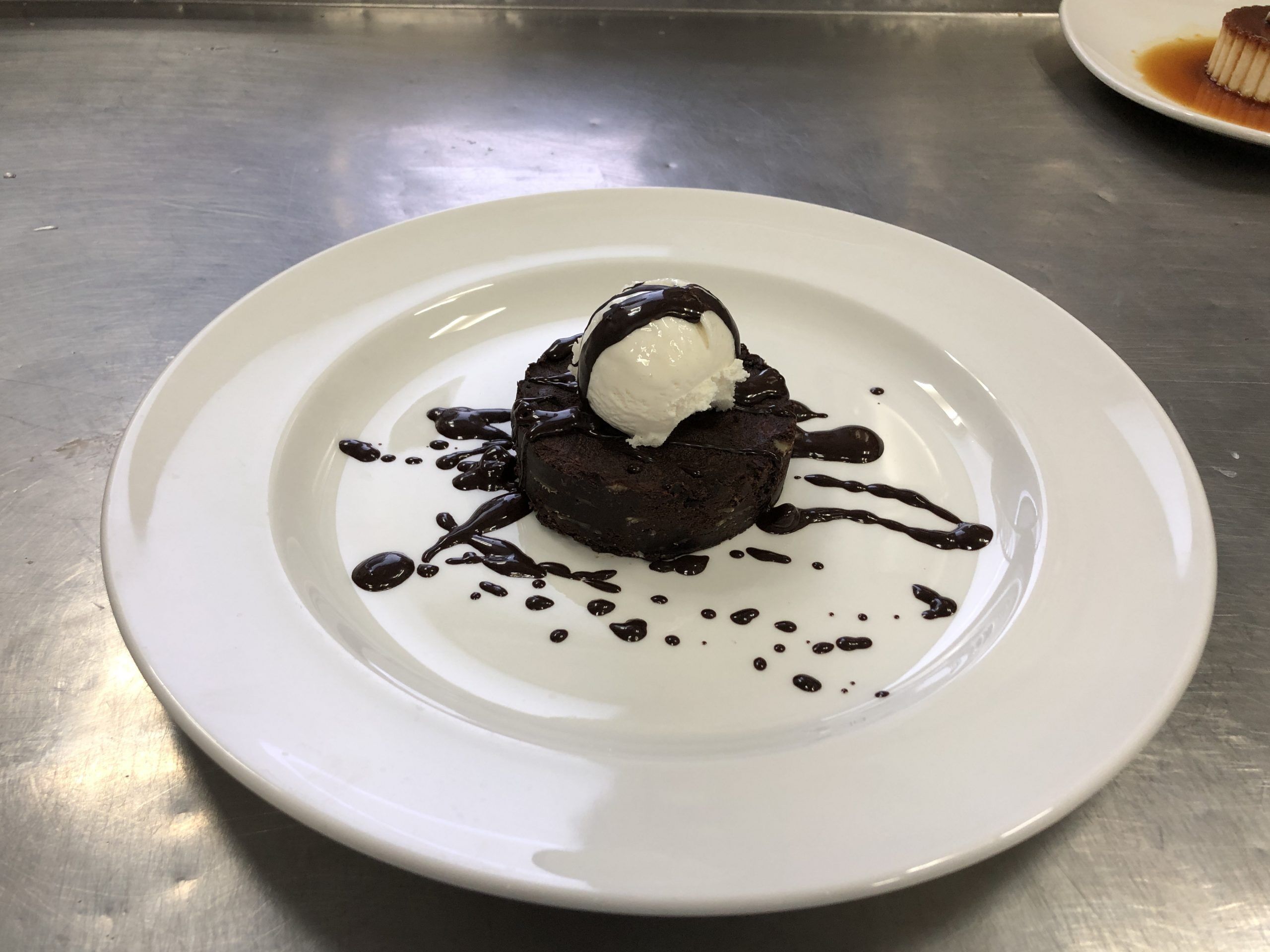 A dessert on a white plate with chocolate sauce and a scoop of ice cream.