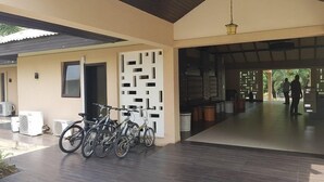 A covered outdoor area with bicycles parked, a building entrance, and a view of the outside. - Epe Resort and SPA (Epe)