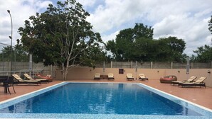 A rectangular swimming pool with tiled edges, surrounded by lounge chairs and a tiled deck area. - Epe Resort and SPA (Epe)