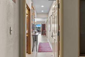 Un pasillo con una puerta de madera, un tapete rojo y vista a un comedor.