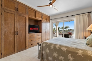 Ein Schlafzimmer mit Bett, Holzschränken, einem Fernseher und einem Balkon mit Blick.