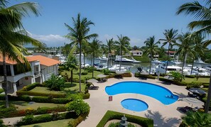 Ein Resort mit einem großen Swimmingpool, umgeben von gepflegten Gärten und Palmen.