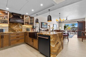 Une cuisine moderne avec des meubles en bois, un îlot en marbre et des luminaires suspendus.