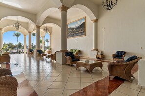 A spacious lobby with a tiled floor, wicker furniture, and a painting on the wall. - Condominio 1HAB/Balcón - Grand Marina Villas (Nuevo Vallarta)