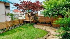 A backyard with a stone pathway, a small lawn, and a bamboo fence.