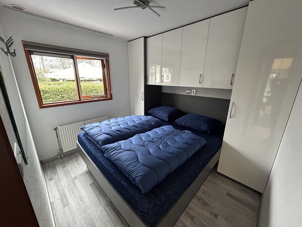 A bedroom with a bed, a window, and a radiator.