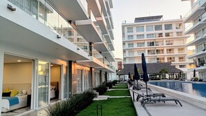 A modern hotel with a swimming pool, outdoor seating, and a well-maintained lawn. - 2BR Exclusive Private Pool • Canal view y Beach (Las Jarretaderas)
