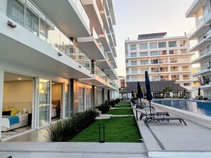 A modern hotel with a swimming pool, outdoor seating, and a well-maintained lawn. - 2BR Exclusive Private Pool • Canal view y Beach (Las Jarretaderas)