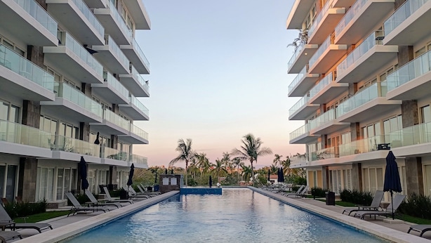 A modern hotel with a central swimming pool, multiple balconies, and outdoor seating areas. - 2BR Exclusive Private Pool • Canal view y Beach (Las Jarretaderas)