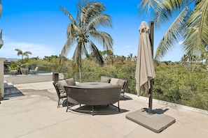 An outdoor patio with a round table and chairs, surrounded by palm trees and a view of the landscape. - 2BR Residence • Private Pool • Canal • Beach (Las Jarretaderas)