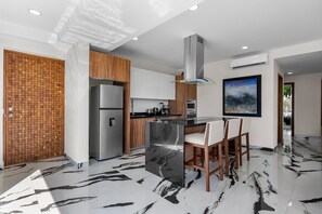 Une cuisine moderne avec un sol en marbre, des appareils électroménagers en acier inoxydable et des meubles de rangement en bois.
