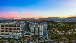 A multi-story hotel with balconies, a swimming pool, and a view of the mountains. - 2BR Residence • Private Pool • Canal • Beach (Las Jarretaderas)
