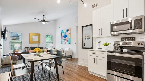 Una cocina moderna con gabinetes blancos, electrodomésticos de acero inoxidable y un comedor con mesa y sillas.