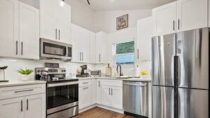 Una cocina moderna con armarios blancos, electrodomésticos de acero inoxidable y suelo de madera.