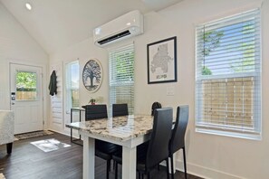 A dining area with a marble table and black chairs, a white ceiling, and a framed map on the wall.