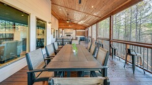 Un espace repas abrité, avec une longue table, des chaises et des ventilateurs de plafond.