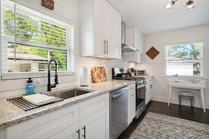 A modern kitchen with white cabinets, a granite countertop, a stainless steel sink, and a built-in oven.
