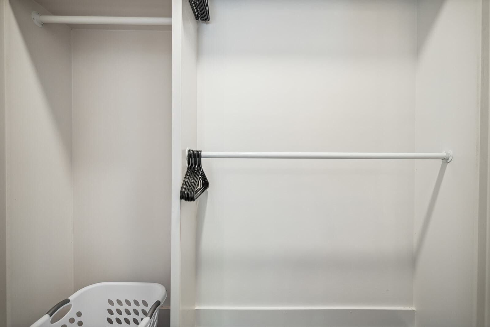 A bathroom with a white bathtub, a white towel rack, and a white laundry basket.