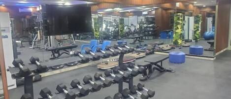 Un gimnasio con varios equipos de ejercicio, incluyendo mancuernas y bancos.