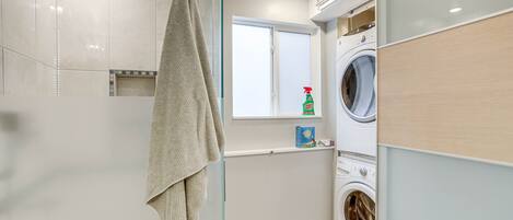 Une salle de bain moderne dotée d’une douche à parois de verre, d’un lave-linge encastré et d’une fenêtre offrant une vue agréable.