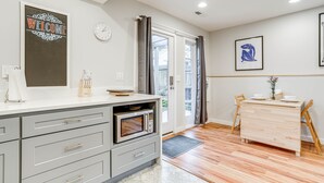Une cuisine moderne avec des meubles de couleur grise, un four à micro-ondes encastré et une table à manger en bois avec des chaises.
