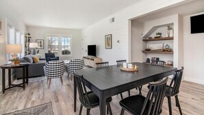 Ein modernes Wohnzimmer mit einem dunkelholznen Esstisch, schwarzen Stühlen, einem grauen Sofa und einem Couchtisch.