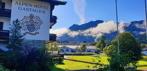 The Alpen-Hotel Gastager with a mountain backdrop, a stone wall, and a clear sky. - Alpenhotel Gastager (Inzell)