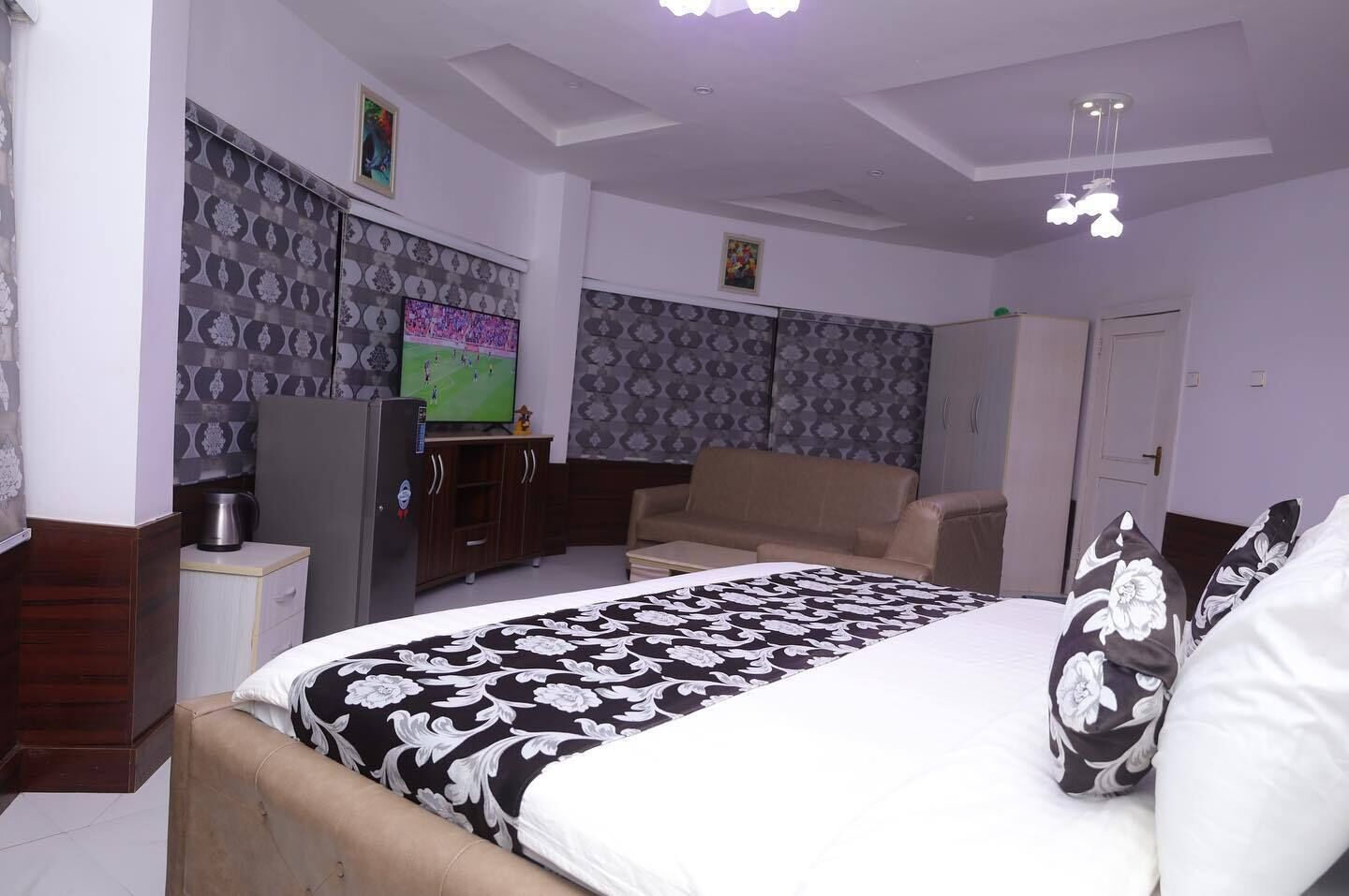 A bedroom with a bed, a television, a wardrobe, and a sofa.