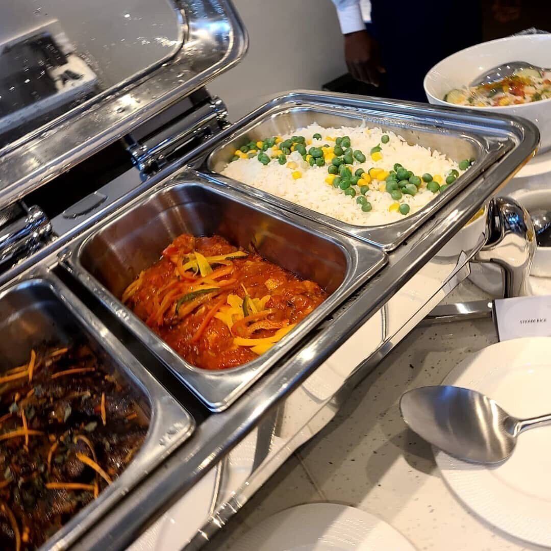 A buffet with various dishes including rice, peas, and a meat dish.