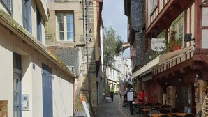 Eine Kopfsteinpflasterstraße mit Gebäuden an beiden Seiten, darunter ein Restaurant mit Außenbereich.