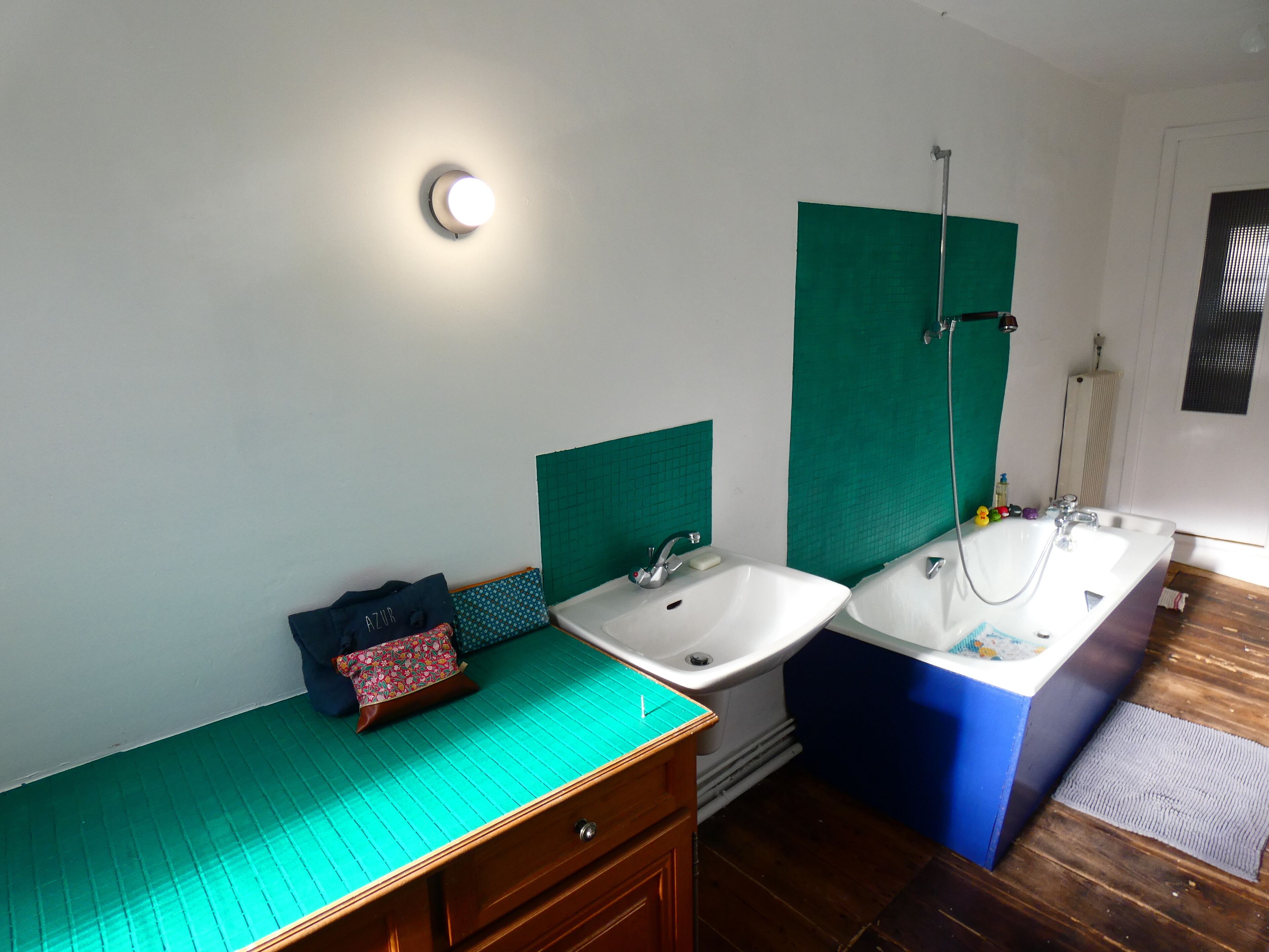 Ein Badezimmer mit zwei Waschbecken, einer Dusche, einem Holzschrank und einer grünen Matte auf dem Boden.