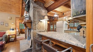 Une cuisine rustique avec une cheminée en pierre, des poutres en bois et un plan de travail en granit.