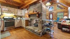 Une cuisine rustique avec des meubles en bois, une cheminée en pierre et un coin repas comprenant une table et des chaises.