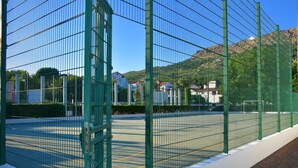 Aidattu tenniskenttä, jolta on esteetön näkymä ympäröiviin rakennuksiin ja vuorille.