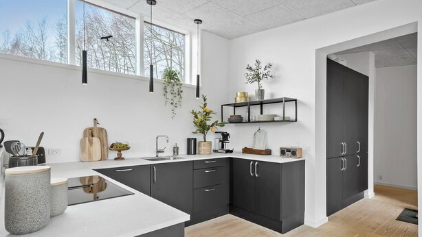 A modern kitchen with dark cabinets, a white countertop, and a large window. - Cozy home in Aakirkeby with WiFi (Aakirkeby)