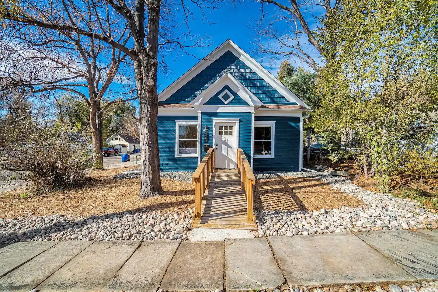 A small blue house with a wooden staircase leading to the front door.