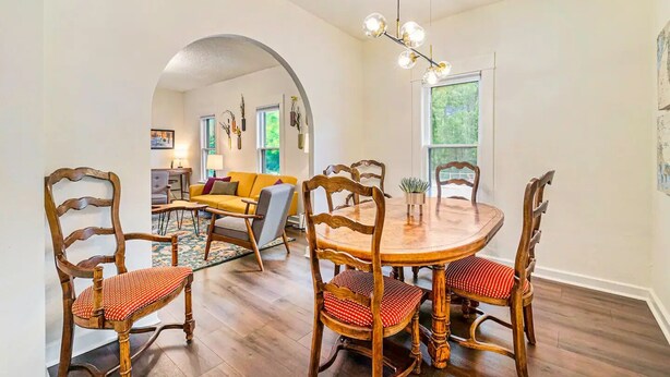 A dining area with a wooden table and chairs, a yellow sofa, and a chandelier. - Downtown Loveland Bungalow, charming, historic 2BR recently remodeled gem. 

 (Loveland)