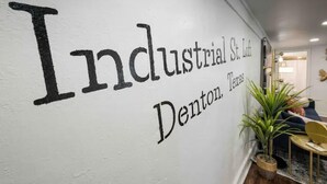 A wall with the text "Industrial St. Loft Denton, Texas" in a bold, black font. - Industrial St. Loft on the square (Denton)