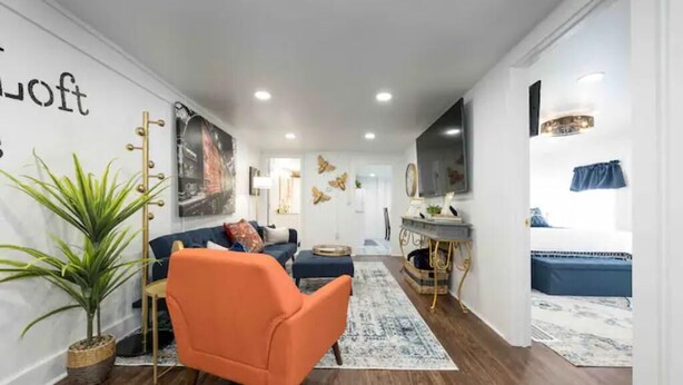 A modern living room with a sofa, a chair, a dining area, and a kitchen. - Industrial St. Loft on the square (Denton)