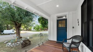 Un portico coperto con pavimento in legno, una porta blu e mobili in vimini.