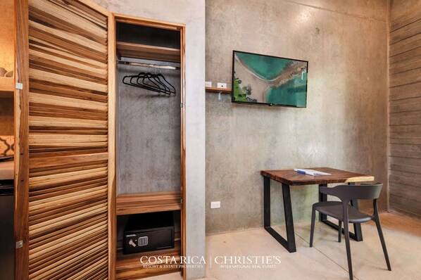 Una habitación moderna con un armario de madera, un televisor de pantalla plana en la pared y una pequeña mesa con una silla.