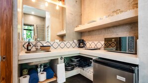 A compact kitchen with a built-in microwave, a coffee maker, and a refrigerator. - Dos Hijas Casita 1-Steps to the Main Surf Break (playa grande)