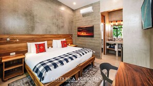 A bedroom with a large bed, wooden headboard, bedside tables, a nightstand, a desk, and a chair. There is a painting on the wall, a window with a view, and an air conditioning unit. - Dos Hijas Casita 1-Steps to the Main Surf Break (playa grande)